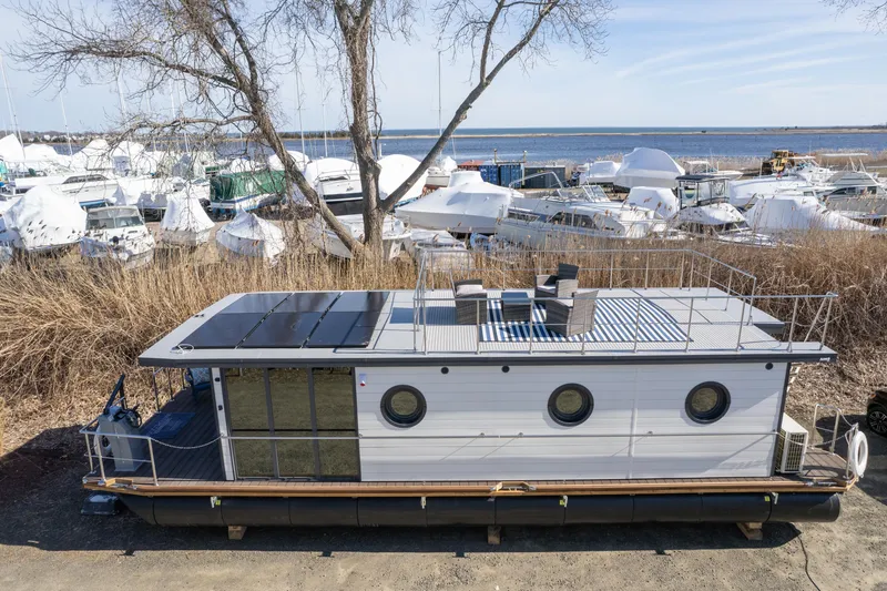 Slide: The Image of 2024 Waterlodge Apart EL houseboat docked near a marina with other boats in the background. - 29