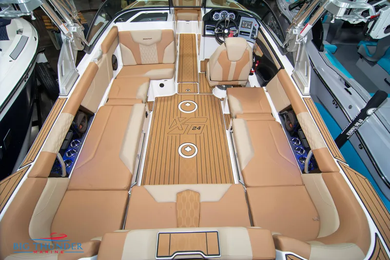 Slide: The Image of 2024 MasterCraft XT24 boat interior with tan seating and teak flooring. - 13