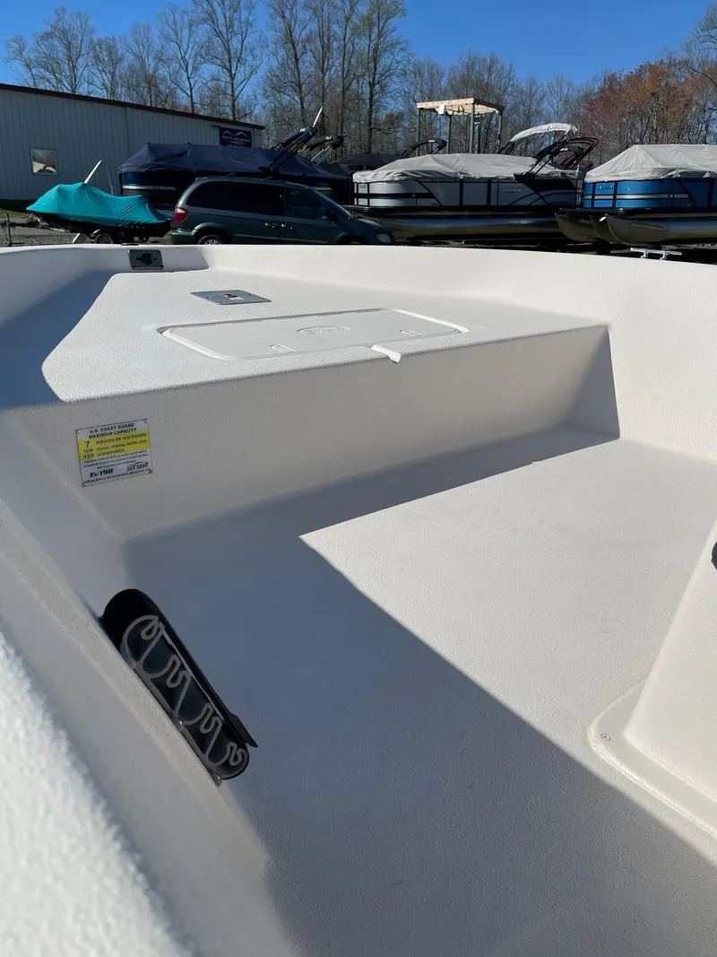Slide: The Image of 2024 Carolina Skiff EV 198 boat interior, white deck, storage compartments, and rod holders. - 7