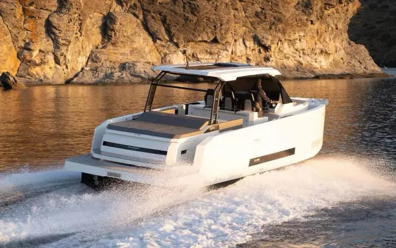 The Image of 2025 De Antonio Yachts D36 OPEN cruising near rocky coastline at sunset. - 0