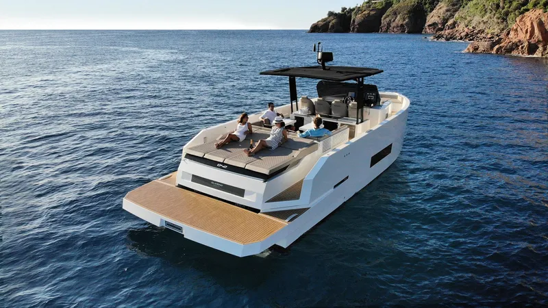 Slide: The Image of 2024 De Antonio Yachts D42 Open cruising on serene blue waters near rocky coastline. - 8