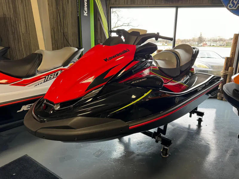 The Image of 2025 Kawasaki STX160LX jet ski in showroom, red and black design. - 1