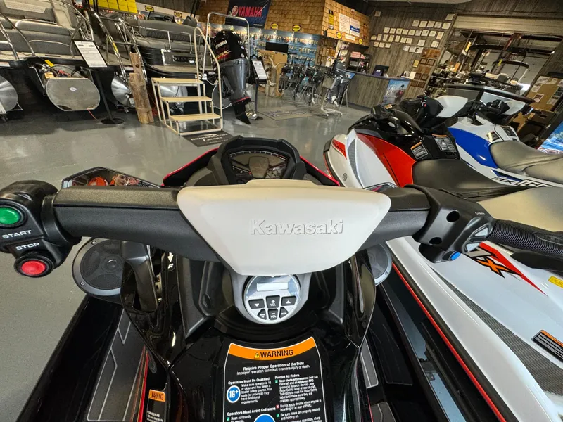 Slide: The Image of 2025 Kawasaki STX160LX jet ski dashboard in showroom, featuring control panel and handlebars. - 3
