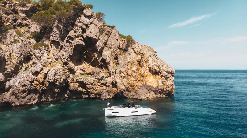 Slide: The Image of 2024 De Antonio Yachts D50 OPEN near rocky coastline in clear blue waters. - 7