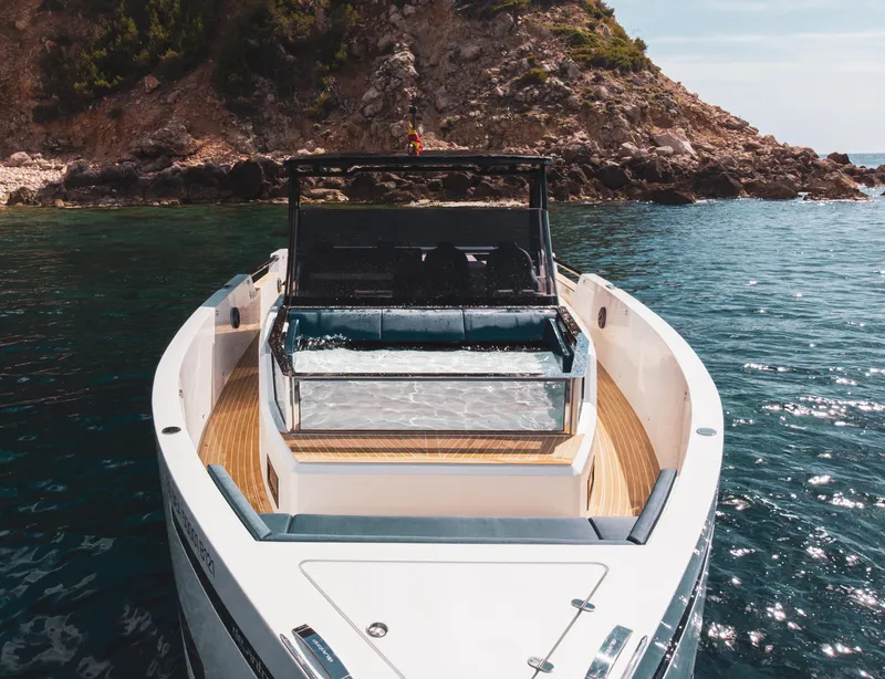 Slide: The Image of 2024 De Antonio Yachts D50 OPEN on serene water near rocky coastline. - 4