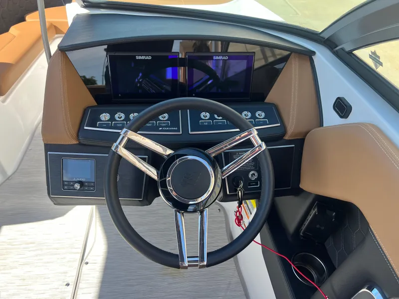 Slide: The Image of 2023 Four Winns H4 boat dashboard with steering wheel and dual Simrad displays. - 12