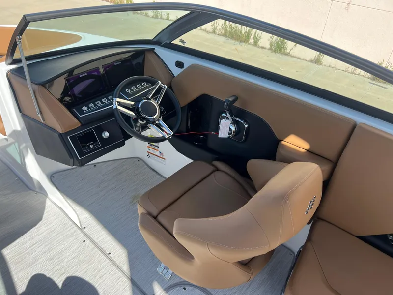 Slide: The Image of 2023 Four Winns H4 boat interior with modern dashboard and tan seating. - 13