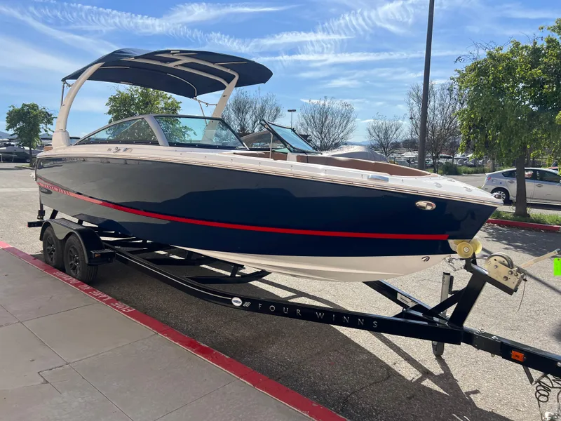 Slide: The Image of 2023 Four Winns H4 boat on trailer, blue hull with red stripe, outdoor display. - 4