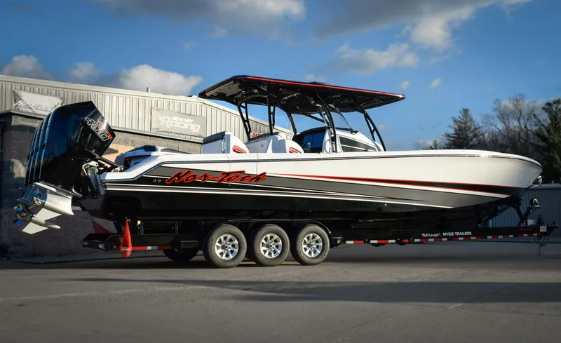 The Image of 2025 Nor-Tech 390 Sport boat on trailer, sleek design, triple engines, parked outdoors. - 0