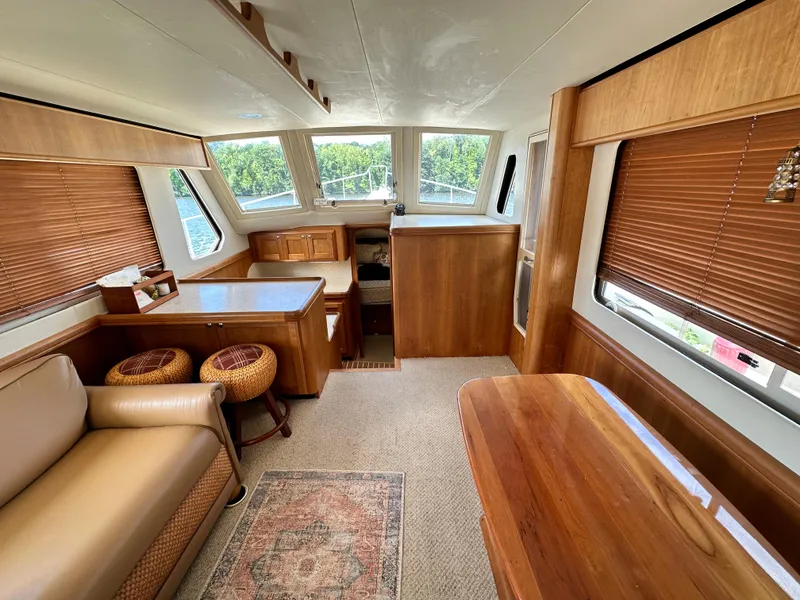 Slide: The Image of Mainship 34 2005 interior with wooden furnishings, seating area, and large windows. - 9