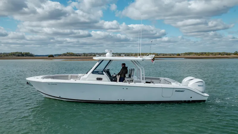 Slide: The Image of 2022 Pursuit S 328 boat cruising on a calm lake under a partly cloudy sky. - 1