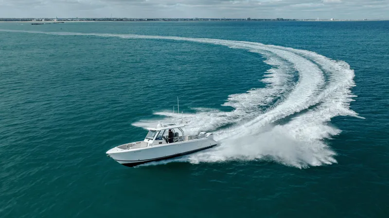 Slide: The Image of 2022 Pursuit S 328 boat cruising on open water, creating a wake. - 16