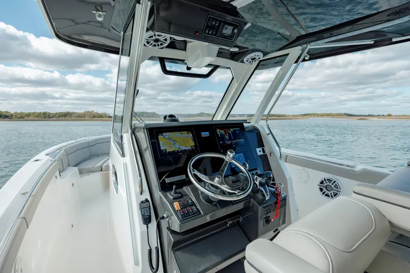Slide: The Image of 2022 Pursuit S 328 boat cockpit with navigation system and steering wheel on open water. - 38