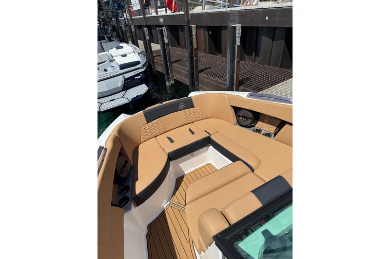 Slide: The Image of 2024 MasterCraft X26 boat interior with tan seating and sleek design at a dock. - 9