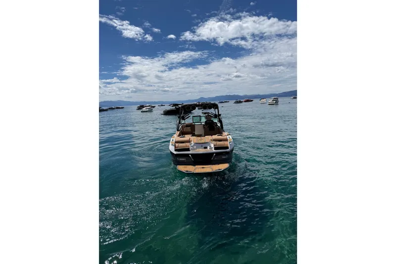 Slide: The Image of 2024 MasterCraft X26 boat on clear blue water under a partly cloudy sky. - 4