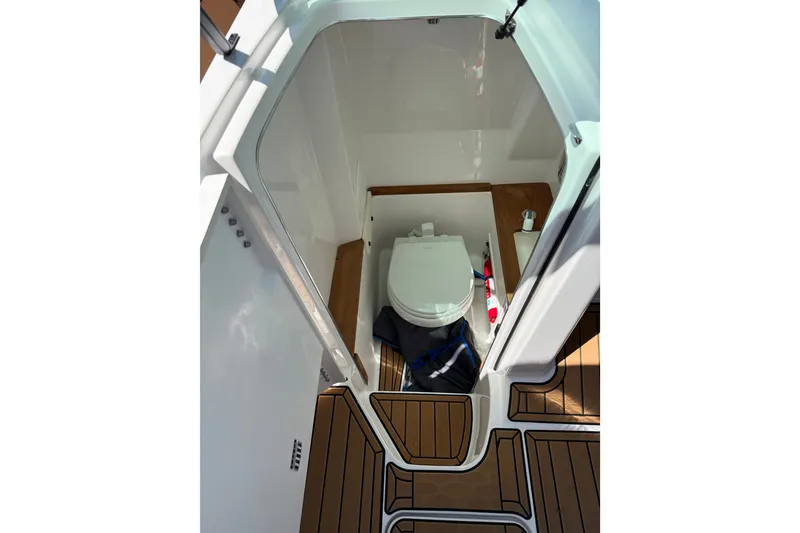 Slide: The Image of 2024 MasterCraft X26 boat interior with compact bathroom and wooden flooring. - 14