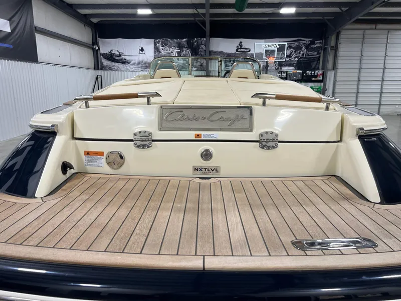 Slide: The Image of 2023 Chris-Craft Launch 27 boat, rear view in a showroom, showcasing teak deck and elegant design. - 15
