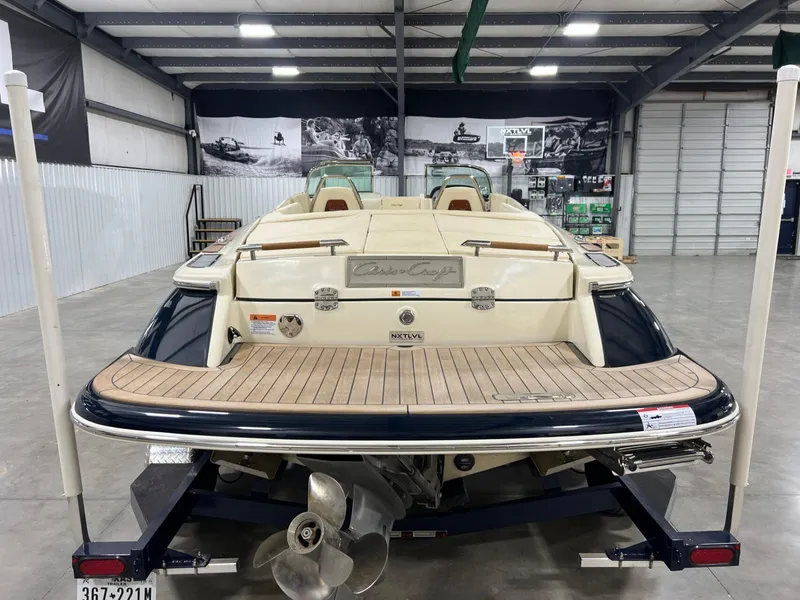Slide: The Image of 2023 Chris-Craft Launch 27 boat in a showroom, rear view with wooden deck. - 18