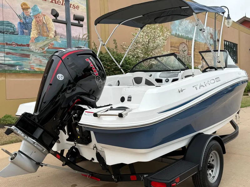 Slide: The Image of 2023 Tahoe 185 S boat on trailer with outboard motor, parked outdoors. - 4