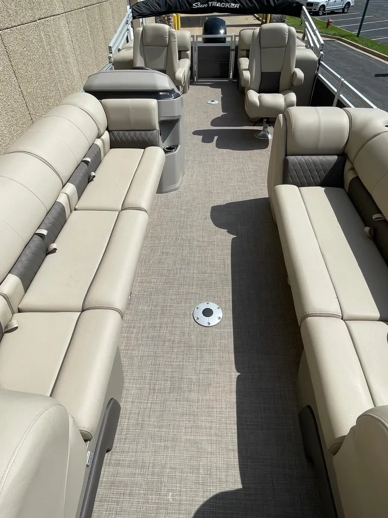 Slide: The Image of 2024 Sun Tracker Party Barge 24 DLX interior with beige seating and spacious layout. - 2