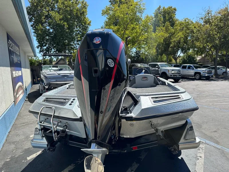 Slide: The Image of 2024 Ranger Z519 boat in parking lot, rear view with motor, surrounded by trees and vehicles. - 10