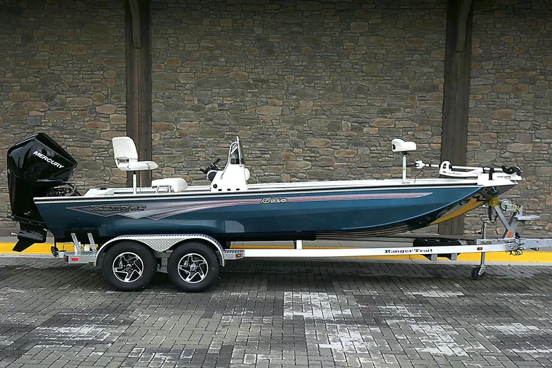 The Image of 2024 Ranger RB210 boat on trailer, side view, against stone wall background. - 0