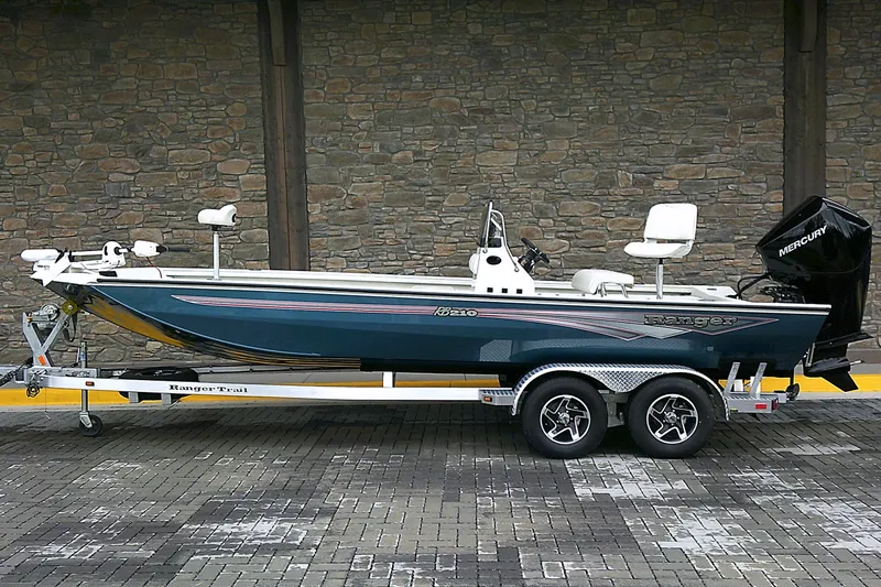 Slide: The Image of 2024 Ranger RB210 boat on trailer, parked against stone wall background. - 1