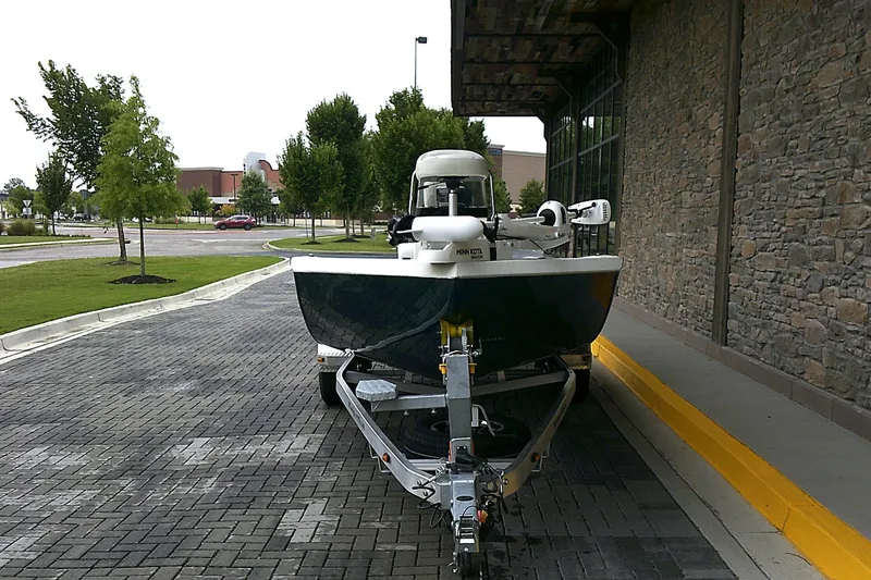 Slide: The Image of 2024 Ranger RB210 boat on trailer, parked on brick pavement near stone building. - 2