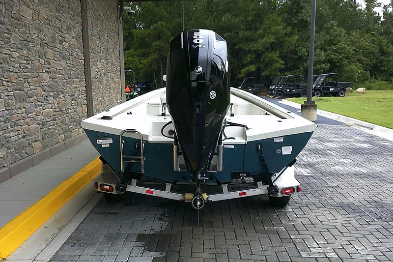 Slide: The Image of 2024 Ranger RB210 boat on trailer, parked on paved area near stone wall and greenery. - 3