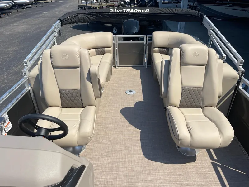 Slide: The Image of 2024 Sun Tracker Party Barge 24 DLX interior with beige seating and steering wheel. - 7
