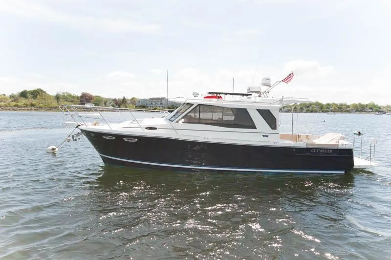 Slide: The Image of 2016 Cutwater 30 Sedan boat on calm water with scenic background. - 0