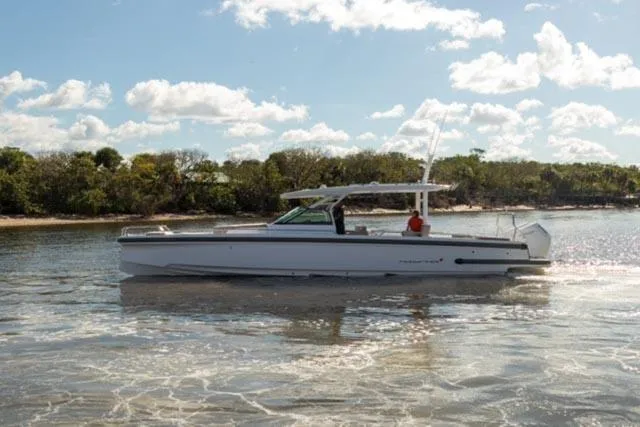 Slide: The Image of 2024 Axopar 37 Sun Top boat cruising on a sunny day near a shoreline. - 10