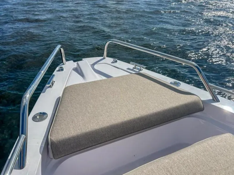 Slide: The Image of 2024 Axopar 37 Sun Top boat bow with cushioned seating on the water. - 12