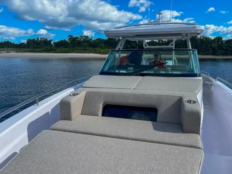 Slide: The Image of 2024 Axopar 37 Sun Top boat on calm water under blue sky. - 15
