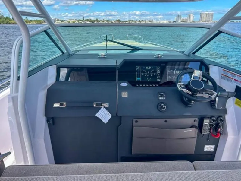 Slide: The Image of 2024 Axopar 37 Sun Top helm with modern controls on open water. - 17