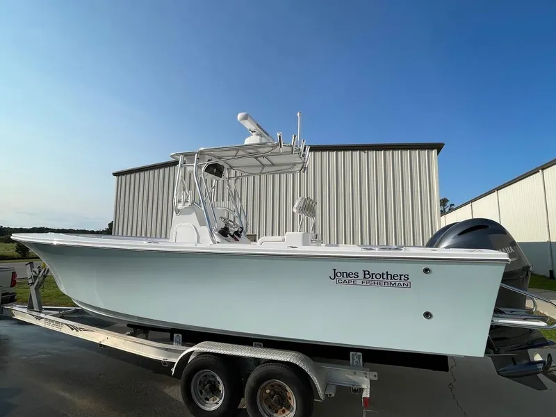 Slide: The Image of 2025 Jones Brothers 26 Cape Fisherman boat with covered console and rod holders. - 14