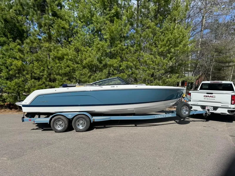 The Image of 2024 Cobalt CS23 boat on trailer, towed by GMC truck, parked near trees. - 0