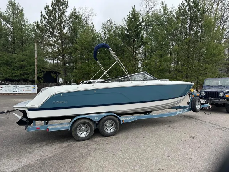 Slide: The Image of 2024 Cobalt CS23 boat on trailer, parked outdoors near trees. - 11