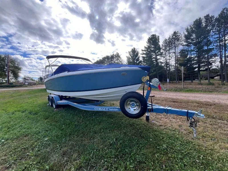 Slide: The Image of 2024 Cobalt CS23 boat on trailer, parked on grassy area under cloudy sky. - 13