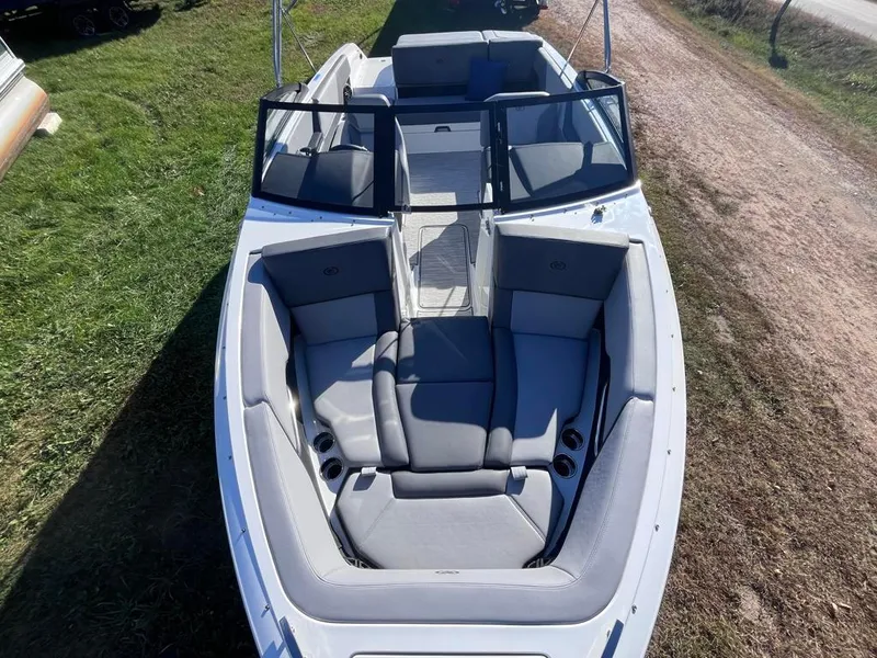 Slide: The Image of 2024 Cobalt CS23 boat with spacious seating and sleek design on grassy terrain. - 23