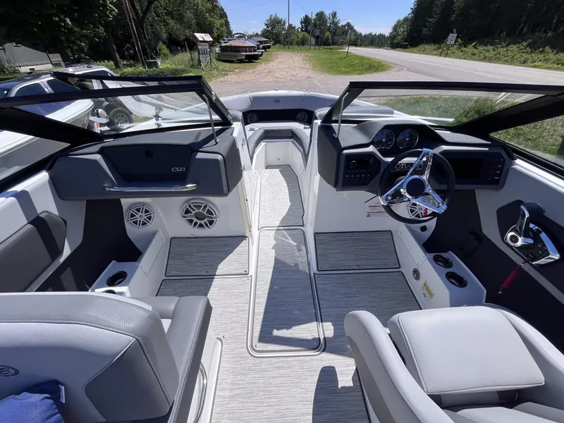 Slide: The Image of 2024 Cobalt CS23 boat interior with modern dashboard and seating, parked near a road. - 25