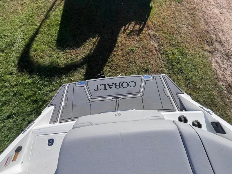 Slide: The Image of 2024 Cobalt CS23 boat deck, gray upholstery, grass background. - 48