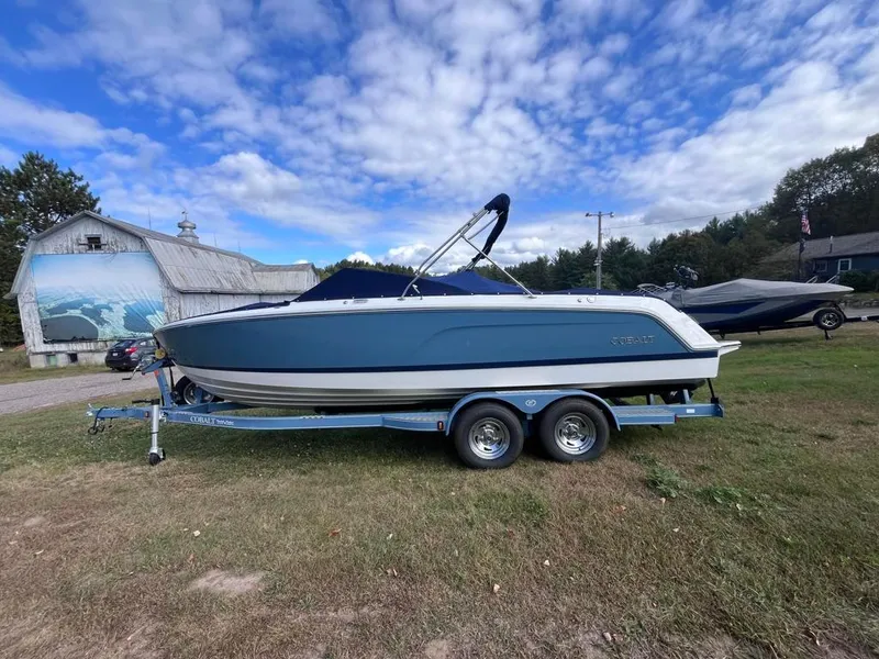 Slide: The Image of 2024 Cobalt CS23 boat on trailer, parked on grass under a partly cloudy sky. - 5