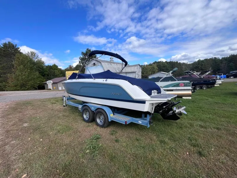 Slide: The Image of 2024 Cobalt CS23 boat on trailer, parked on grass under a partly cloudy sky. - 6