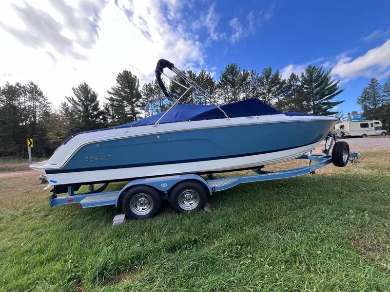 Slide: The Image of 2024 Cobalt CS23 boat on trailer, parked on grass with trees and blue sky background. - 8