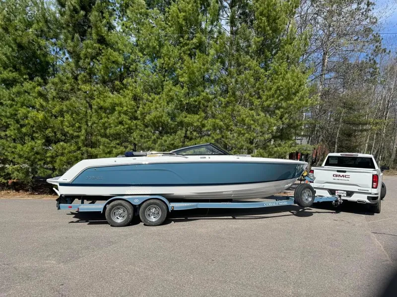 Slide: The Image of 2024 Cobalt CS23 boat on trailer, towed by GMC truck, surrounded by trees. - 9