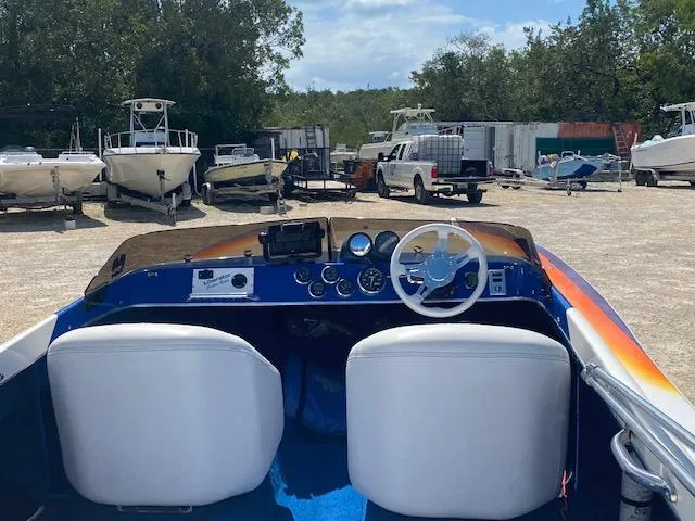 Slide: The Image of 2005 Liberator 21 boat interior with white seats and dashboard in a boatyard. - 2