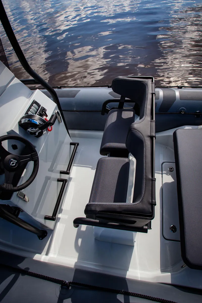 Slide: The Image of 2025 Zodiac Pro 5.5 boat interior with seating and steering wheel on calm water. - 14