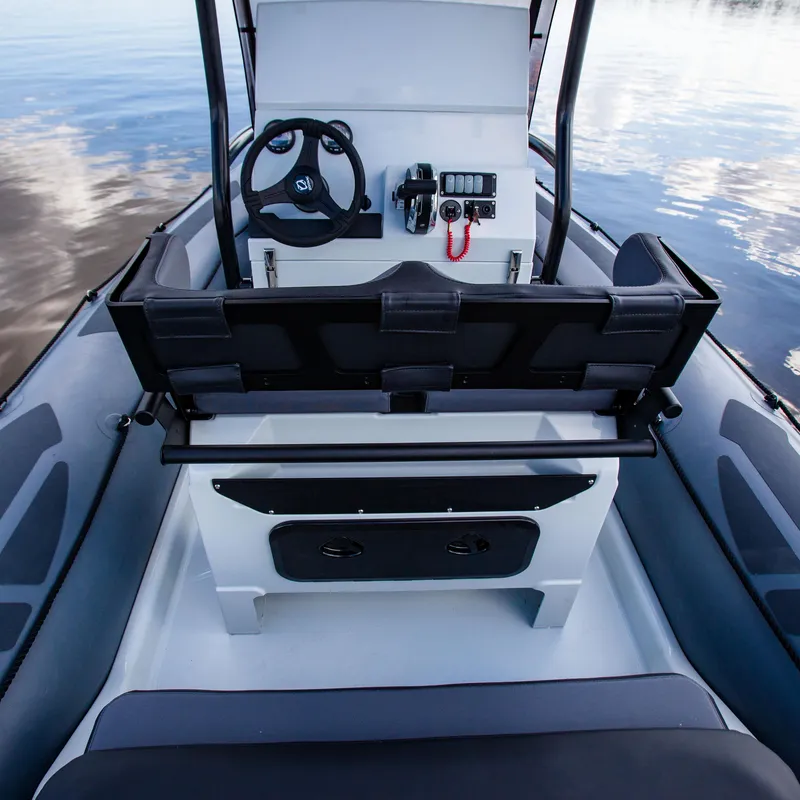 Slide: The Image of 2025 Zodiac Pro 5.5 boat interior with steering console and seating, on calm water. - 16