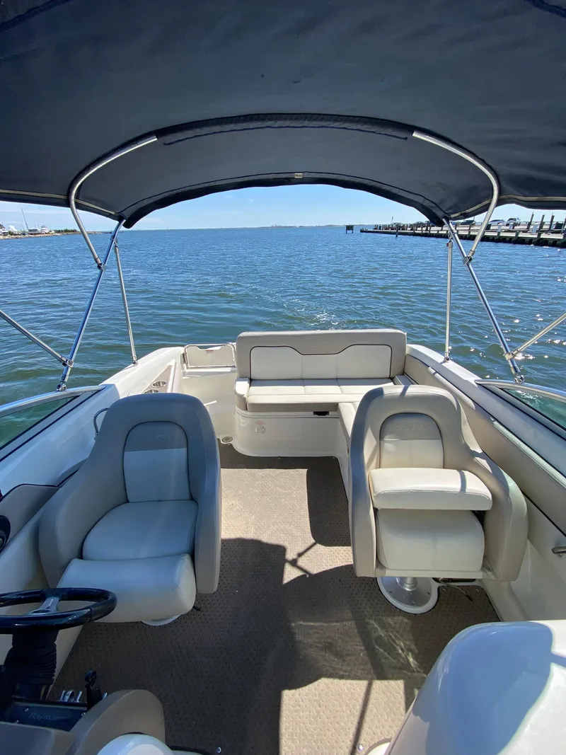 Slide: The Image of 2011 Sea Ray 240 Sundeck boat interior with seating and canopy on the water. - 12